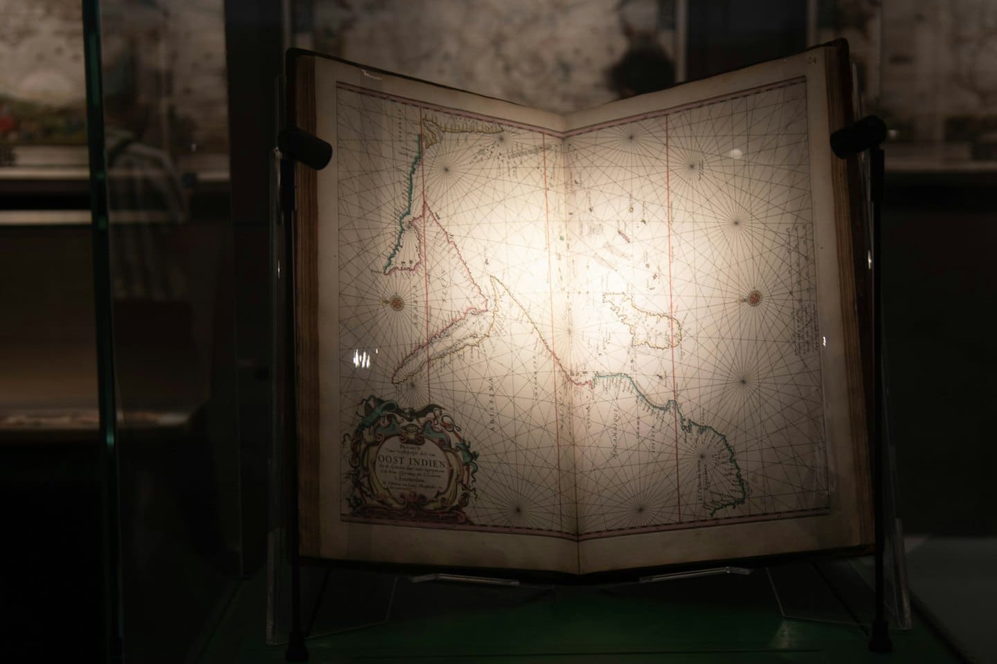 Antique book open to a historical map on a stand.